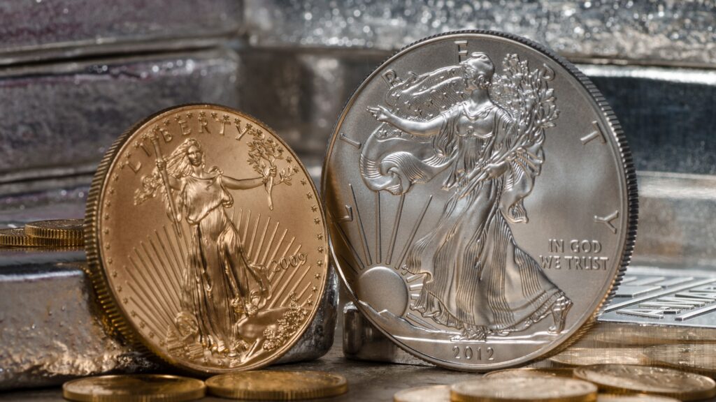 Je ein American Eagle aus Gold und Silber vor Silberbarren